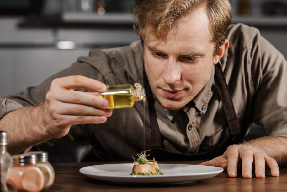 cocinero joven aliñando plato de cocina creativa